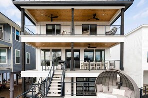 Ein modernes, zweistöckiges Haus mit Balkon, einem großen Fenster und einer Treppe.