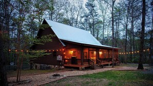 Une cabane en bois avec un porche, entourée d’arbres.