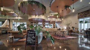 Ein geräumiges Café mit modernem Ambiente, das einen großzügigen Sitzbereich, eine Theke und eine Kreidetafel umfasst.