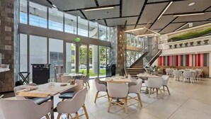 Un restaurant moderne offrant un mélange d’espaces intérieurs et extérieurs, avec un escalier et une vue sur l’extérieur.