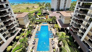 A resort with a central pool, multiple balconies, and a view of the ocean.