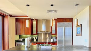A modern kitchen with wooden cabinets, stainless steel appliances, and a central island with bar stools.