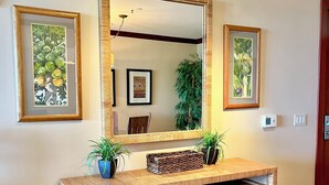A wooden console table with a mirror above it, flanked by two framed botanical prints.