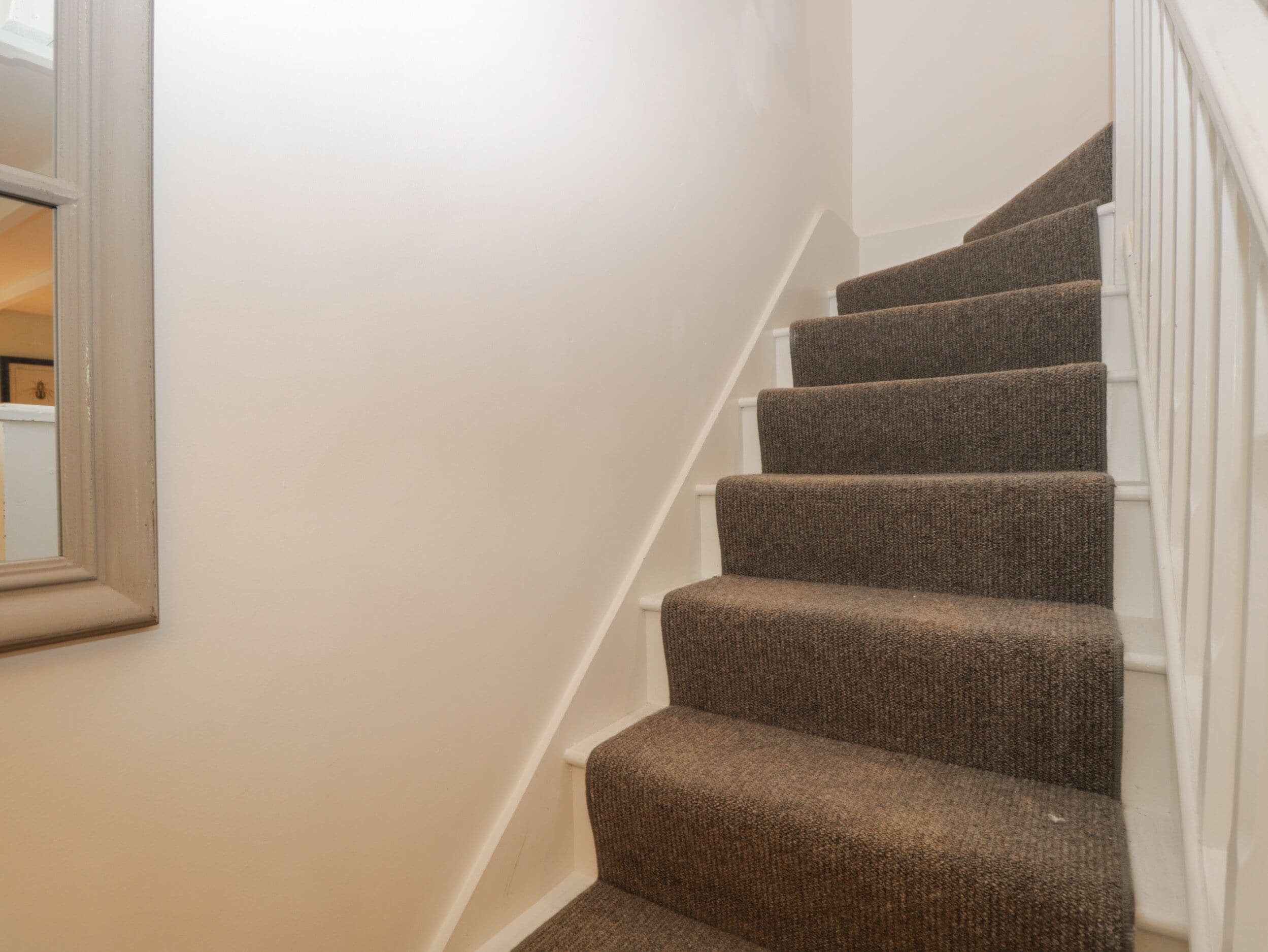 A staircase with carpeted steps and white handrails.