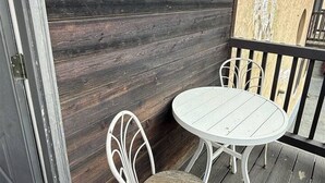 Puinen terassi, jossa on «TERVETULOA»-kyltti, pyöreä pöytä ja kaksi tuolia.
