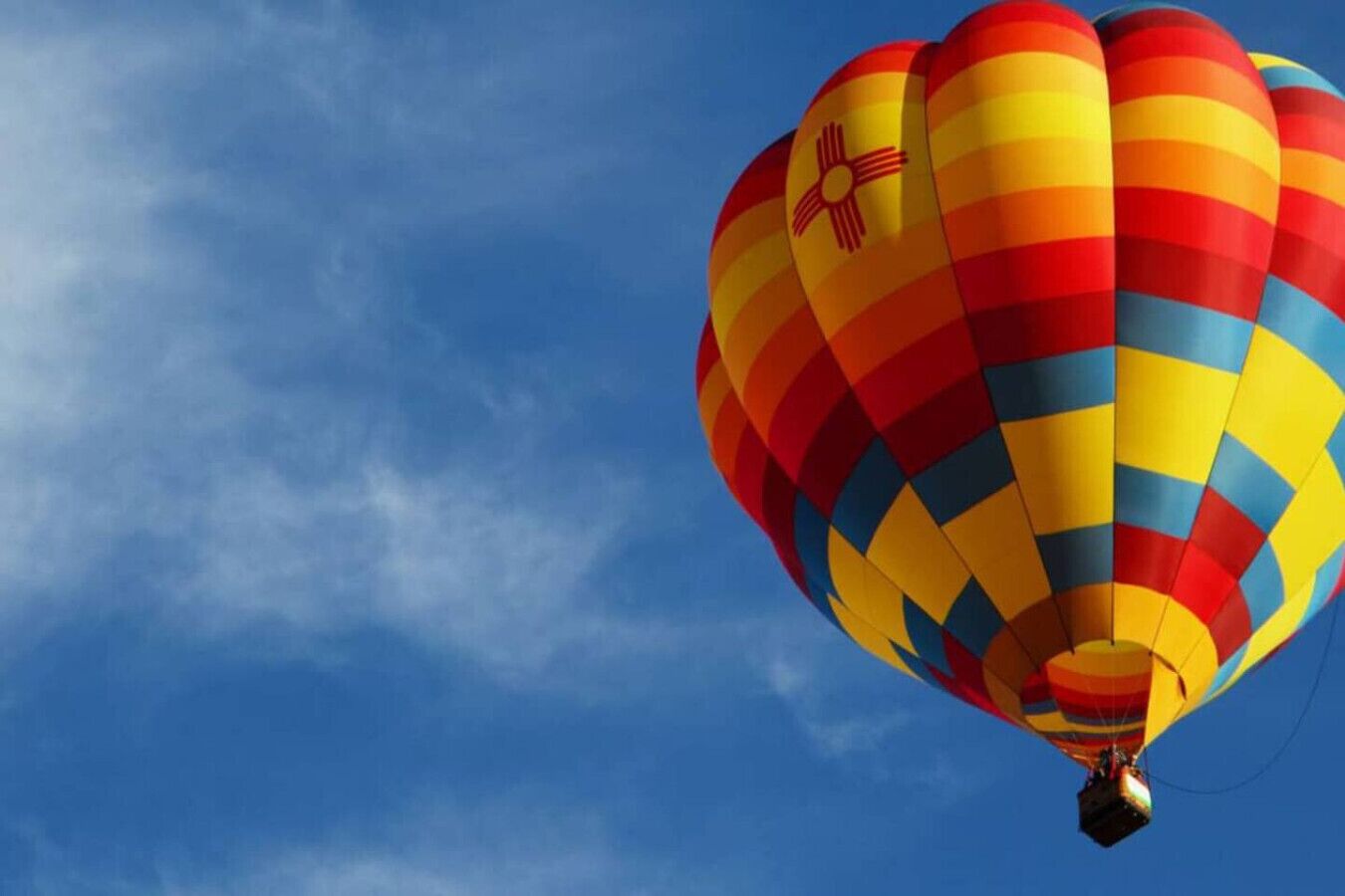 En varmluftsballong med ett färgstarkt mönster mot en klarblå himmel.