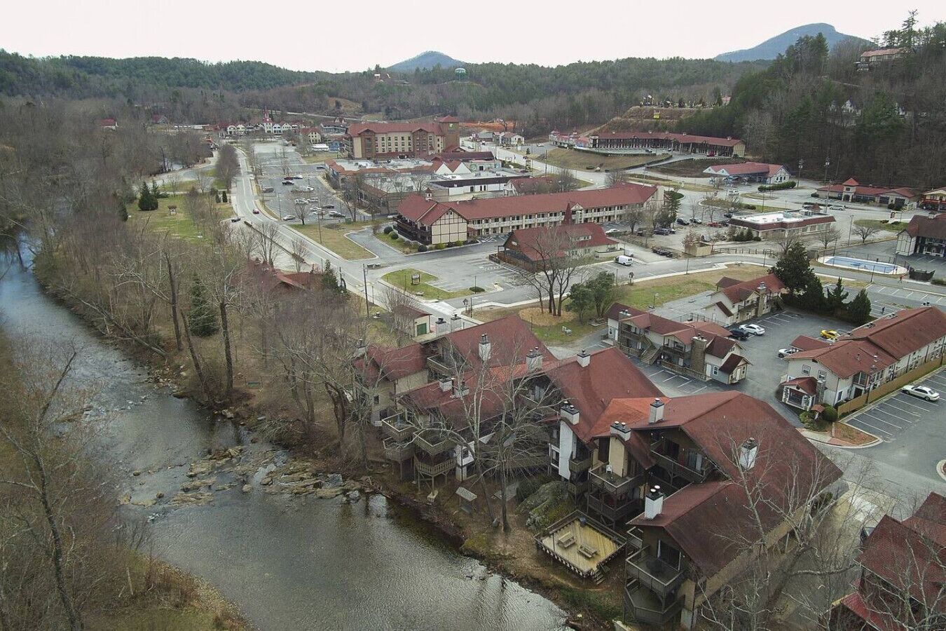 A town with a mix of residential and commercial buildings, a river running through the center, and a hilly backdrop.