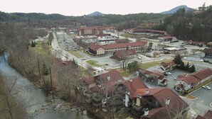 A town with a mix of residential and commercial buildings, a river running through the center, and a hilly backdrop. - Bavarian Brook 7A (Helen)