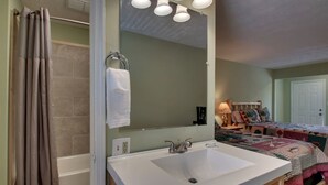 A bathroom with a white sink, a towel rack, and a shower curtain. - Bavarian Brook 7A (Helen)