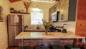 A kitchen with a wooden island, green bar stools, a stainless steel refrigerator, and a window with blinds. - Bavarian Hideaway 25 (Sautee Nacoochee)