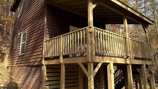 Una cabaña de madera con balcón, rodeada de árboles.