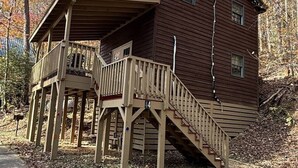 Una cabaña de madera con un porche y una escalera que lleva a la entrada principal.