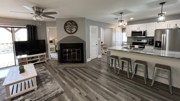 A modern kitchen with a large island, bar stools, and a fireplace. - Rivers Edge 102 (Helen)