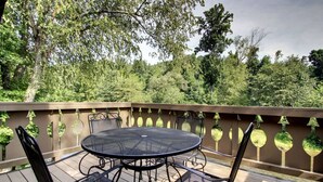 A deck with a round table and four chairs, surrounded by a wooden railing with hanging planters. - Rivers Edge 504 (Helen)