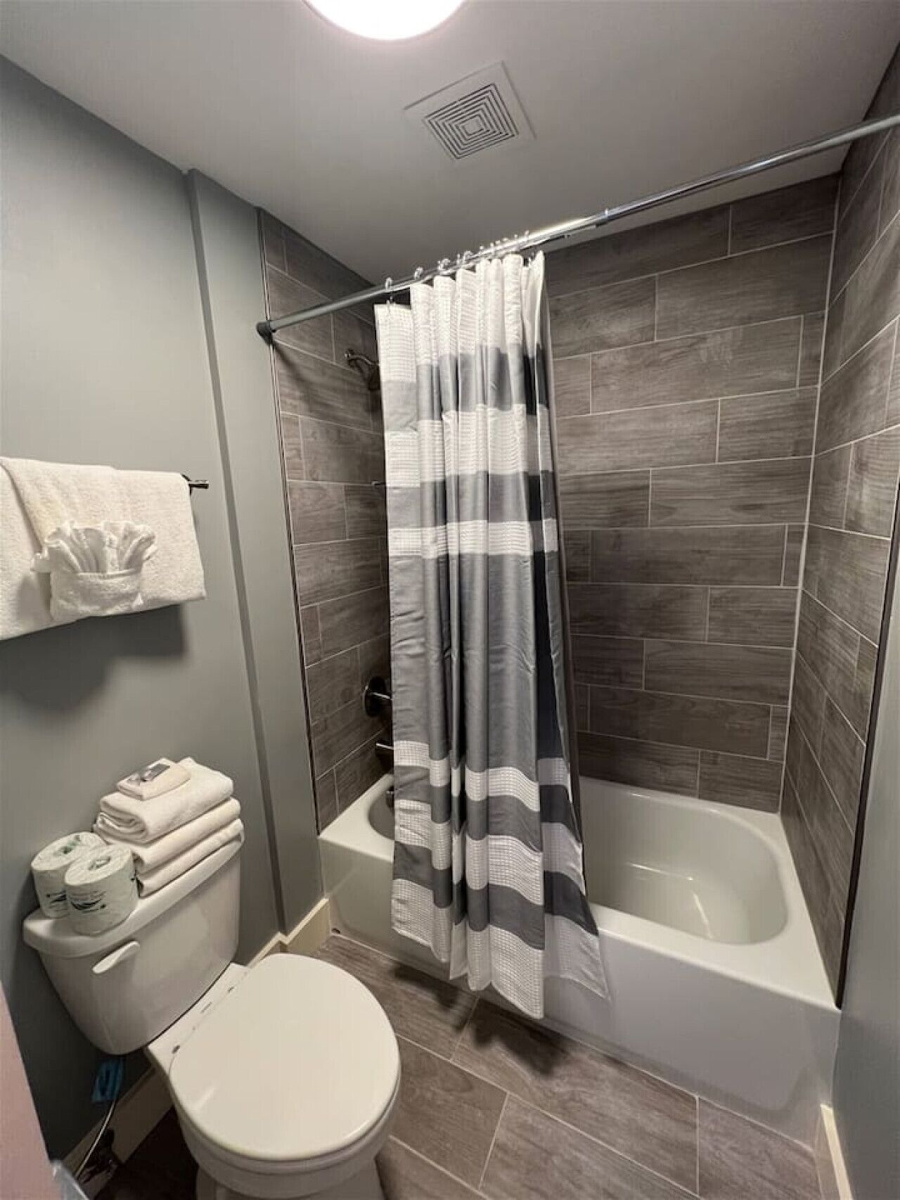 Ein Badezimmer mit Dusche, Toilette und einem Handtuchhalter mit Handtüchern.