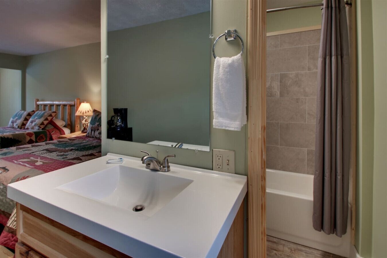 A bathroom with a white sink, a mirror, and a shower.