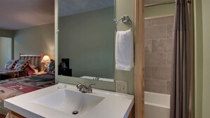 Une salle de bain avec un lavabo blanc, un miroir et une douche.