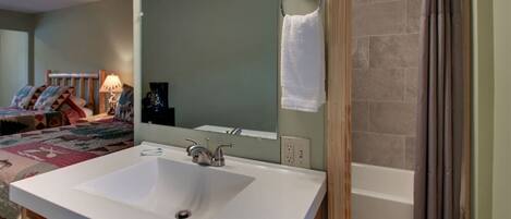 A bathroom with a white sink, a mirror, and a shower.