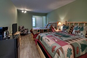 A room with two beds, a coffee maker, a chair, and a door. - Bavarian Brook 8a (Helen)