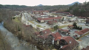 Un quartier résidentiel composé de plusieurs maisons, un bâtiment central doté d’un toit rouge, et une rivière qui traverse le paysage.