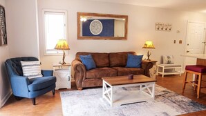 Un salon avec un canapé marron, un fauteuil bleu et une table basse.
