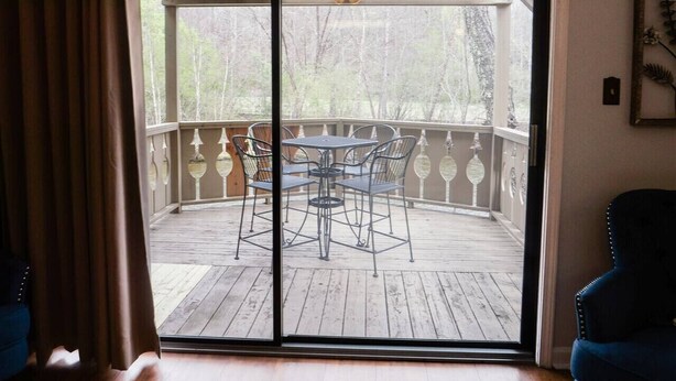 Une porte-fenêtre coulissante donnant sur une terrasse en bois avec une table et des chaises.