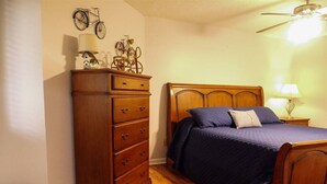 Une chambre avec un lit en bois, une commode et une décoration représentant un vélo au mur.
