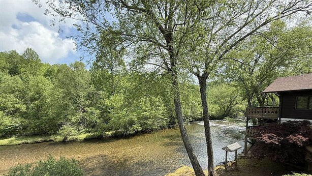 A riverside walkway with a wooden bench and a small structure with a roof. - Rivers Edge 802 (Helen)