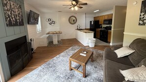 A living room with a fireplace, a sofa, a coffee table, and a kitchen in the background. - Rivers Edge 802 (Helen)