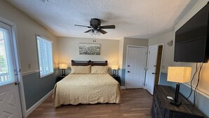 A bedroom with a bed, two bedside tables, a ceiling fan, a TV mounted on the wall, and a dresser. - Rivers Edge 802 (Helen)
