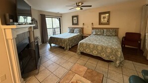 A hotel room with two beds, a fireplace, a ceiling fan, and a window with curtains. - Rivers Edge 803 (Helen)