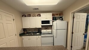 A compact kitchen with white cabinets, a microwave, a stove, and a refrigerator. - Rivers Edge 803 (Helen)