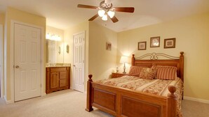 A bedroom with a wooden bed, a ceiling fan, a nightstand, a dresser, and a mirror. - Bavarian Brook Condo 15 (Helen)