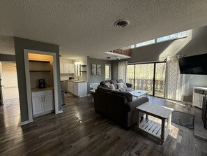 A spacious living area with a sofa, coffee table, and a kitchen in the background.
