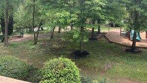 Een park met bomen, een speeltuin en een gazon.