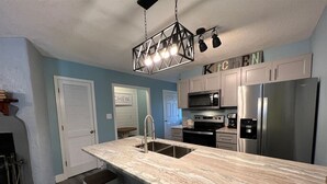 Una cucina moderna con un piano di lavoro in marmo, elettrodomestici in acciaio inossidabile e una lampada a sospensione.
