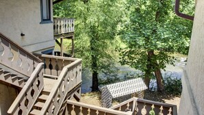 Una scala in legno conduce a un balcone con vista su un fiume e alberi.