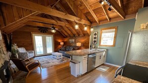 A cozy cabin interior with a wooden ceiling, a kitchen with granite countertops, and a living area with a fireplace. - Bavarian Brook Condo 14 (Helen)