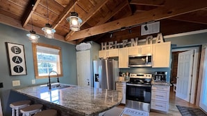A kitchen with a large island, bar stools, a refrigerator, a microwave, and a stove. - Bavarian Brook Condo 14 (Helen)