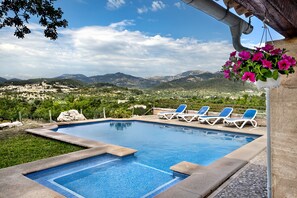 Una piscina con azulejos azules, rodeada de sillas de descanso y una maceta colgante.