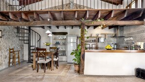 Une cuisine rustique avec des poutres apparentes, un îlot central et un coin repas comprenant des chaises et une table en bois.