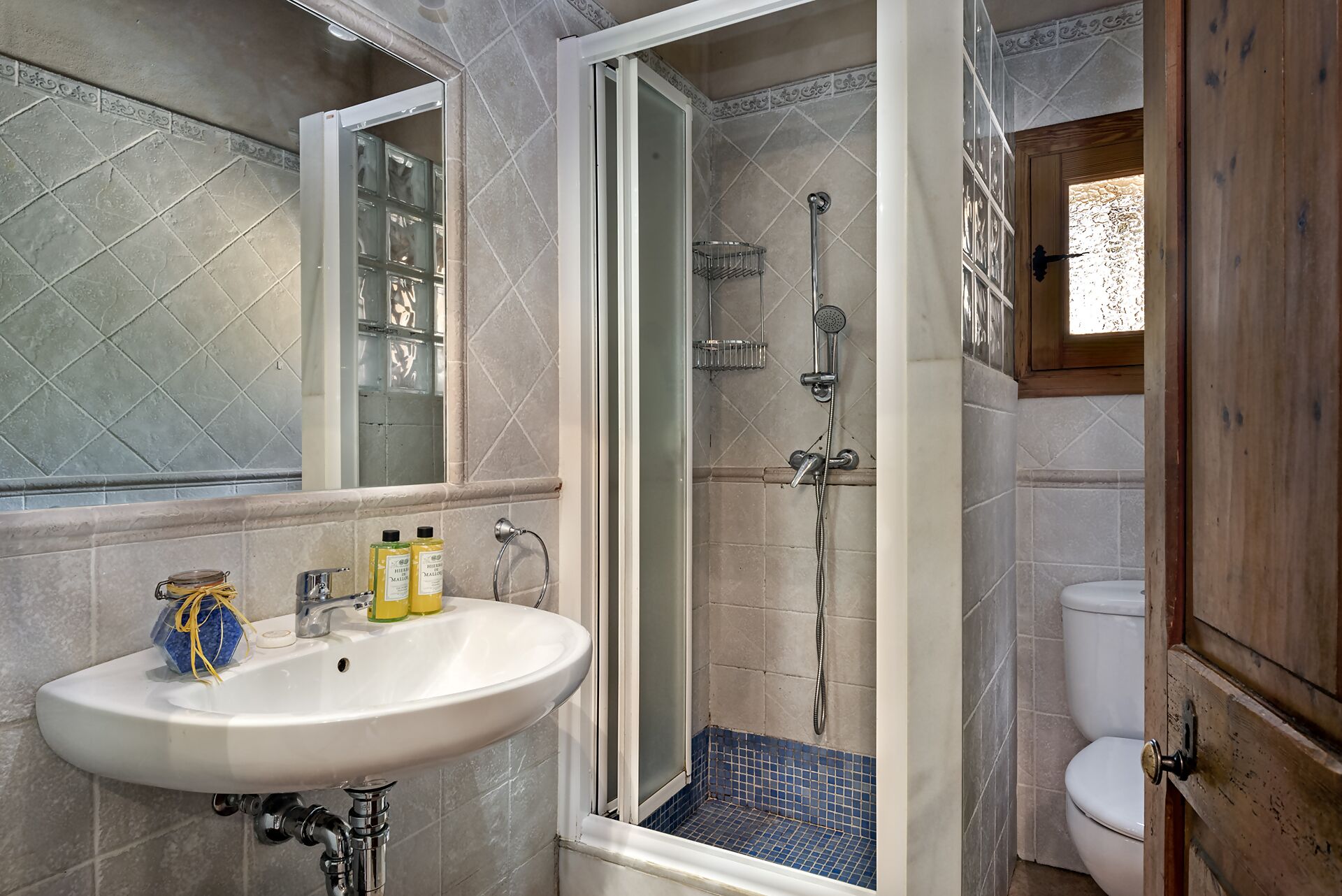 A bathroom with a white sink, a glass shower enclosure, and a toilet.