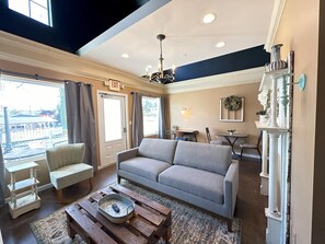 A living room with a sofa, a coffee table, a dining table, and a chandelier.