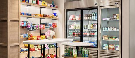 A grocery store with shelves stocked with snacks, beverages, and packaged goods. There are refrigerated sections with bottled drinks and dairy products.