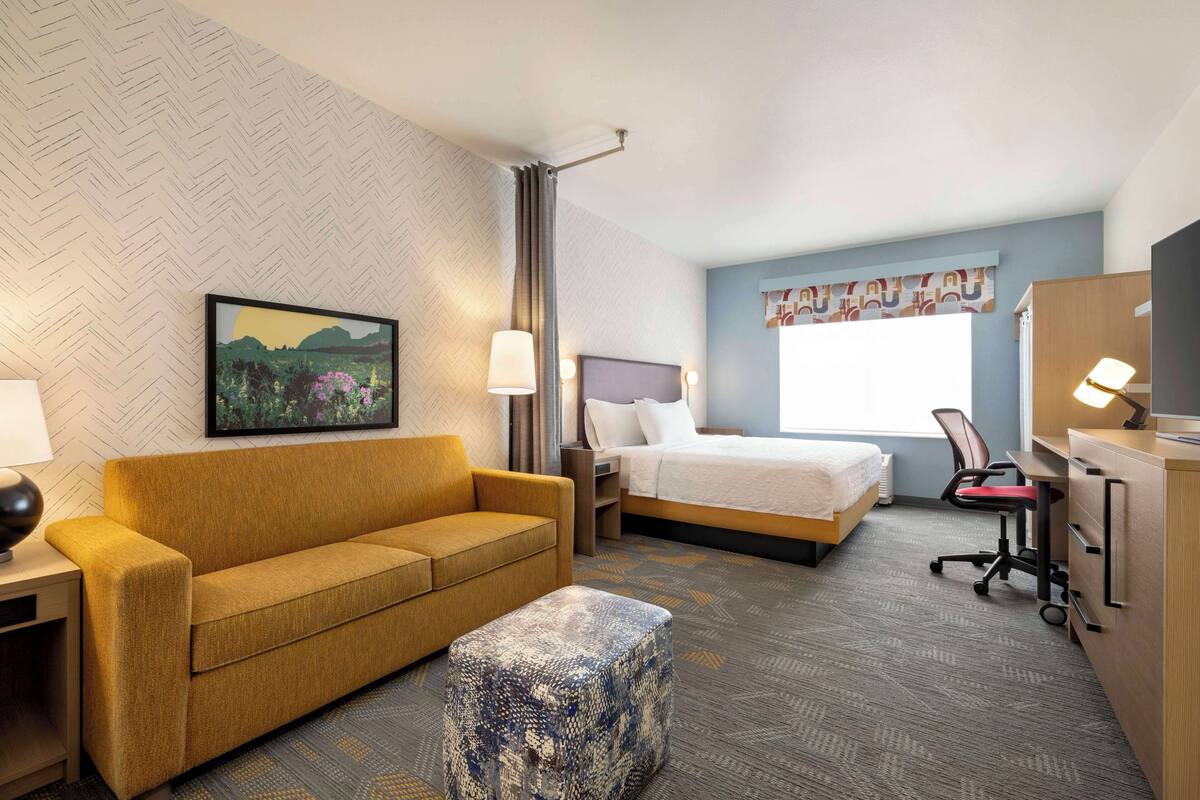 A hotel room with a sofa, a bed, a desk, and a chair.