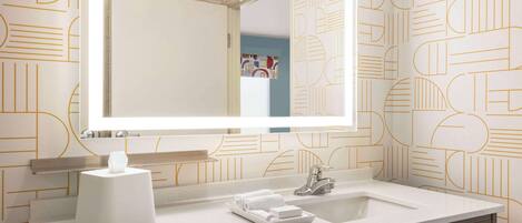 Un baño moderno con un espejo grande, un lavabo y un perchero para toallas.