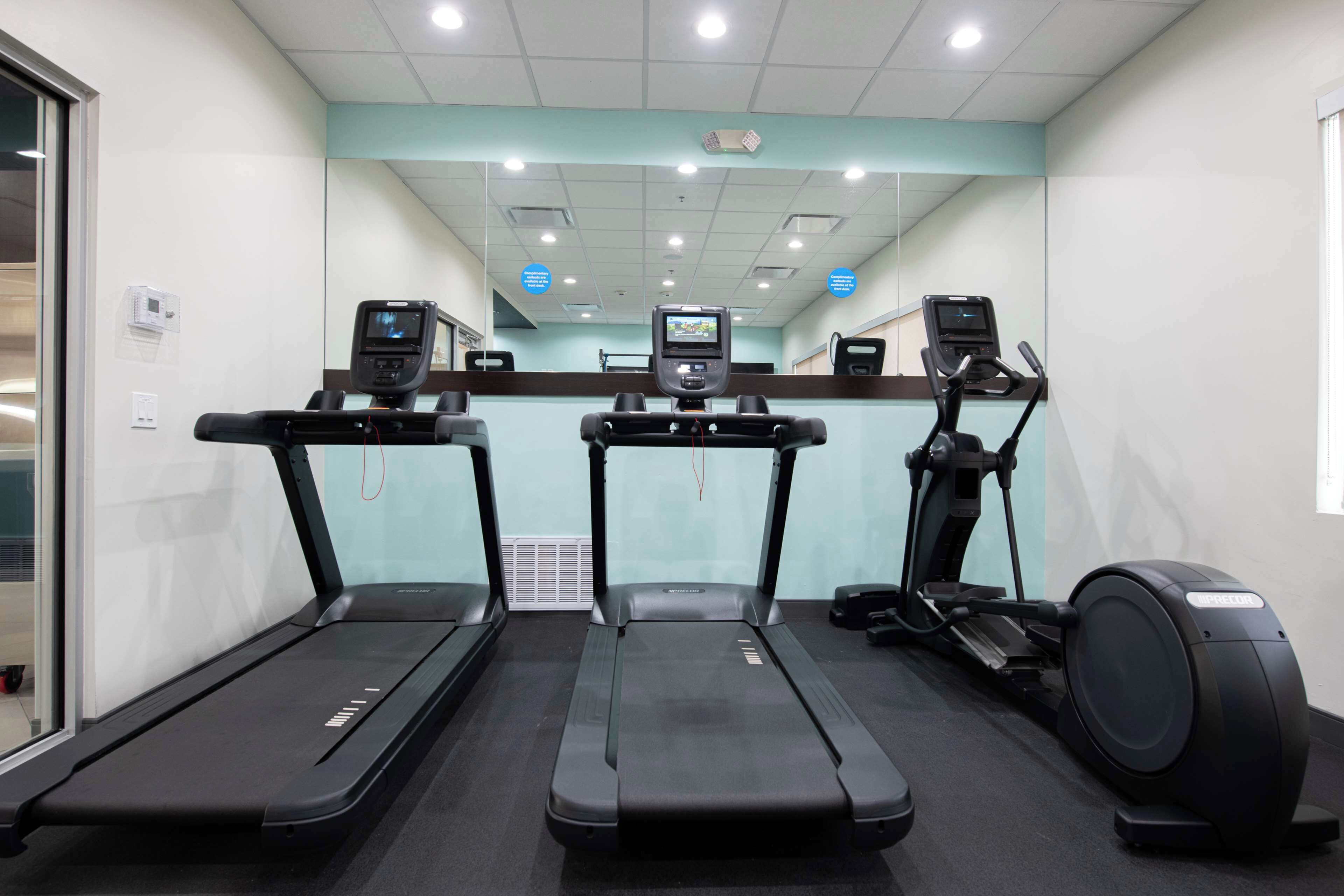 A gym with three treadmills, one elliptical, and a stationary bike.