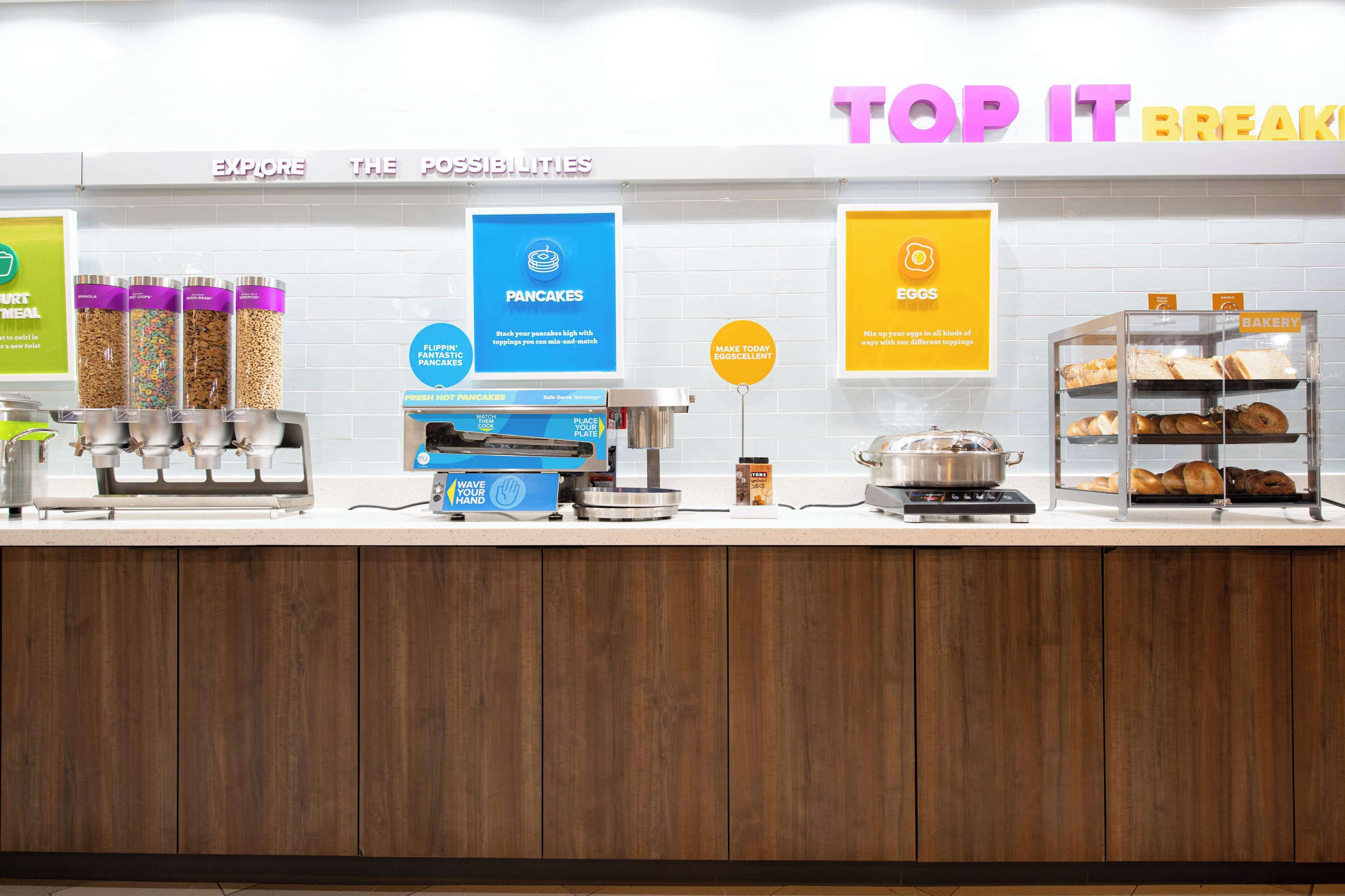 A breakfast counter with various food items and a sign that reads "TOP IT BREAKFAST".