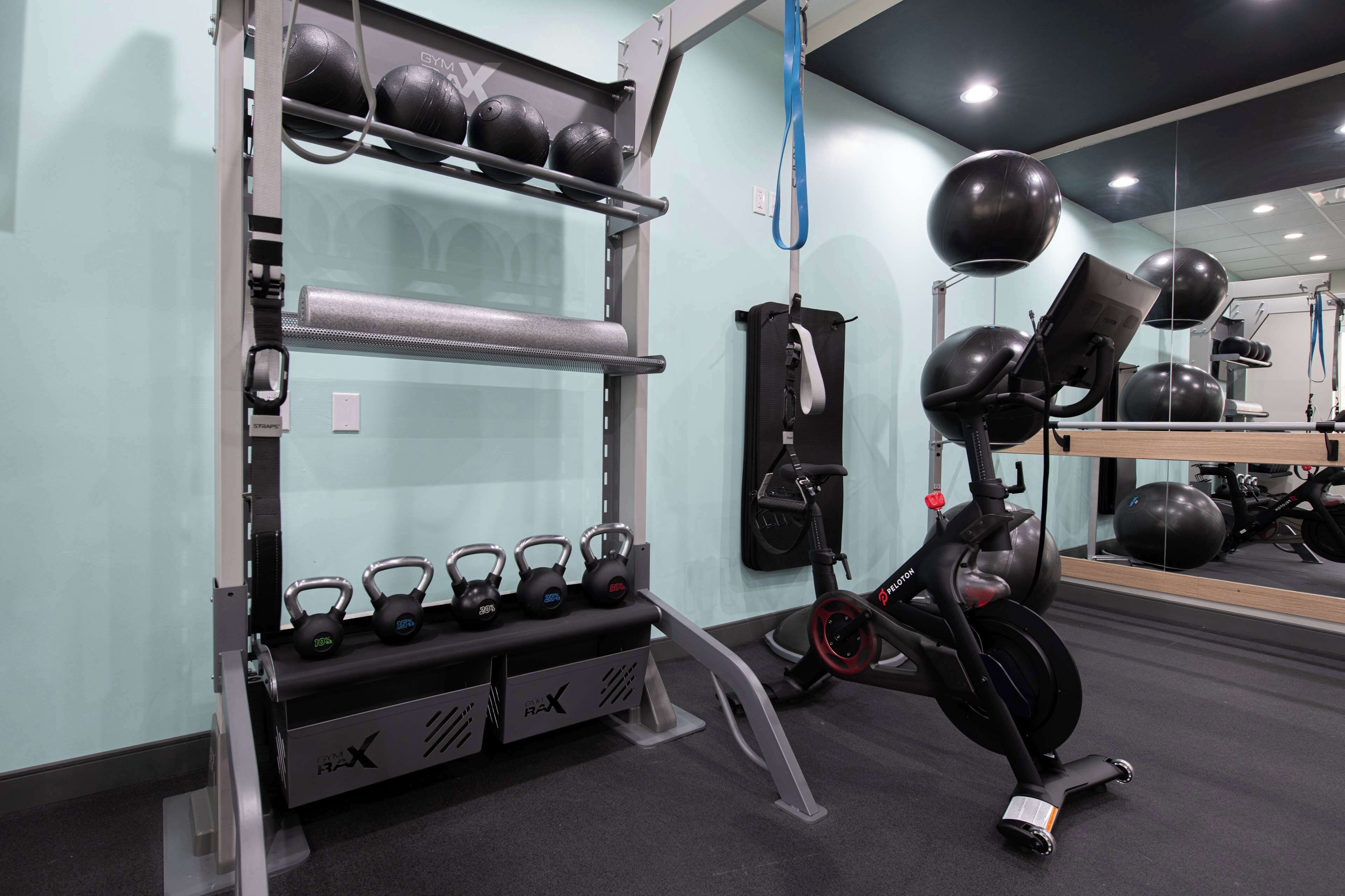 A gym with exercise equipment, including kettlebells, a stationary bike, and a mirror.