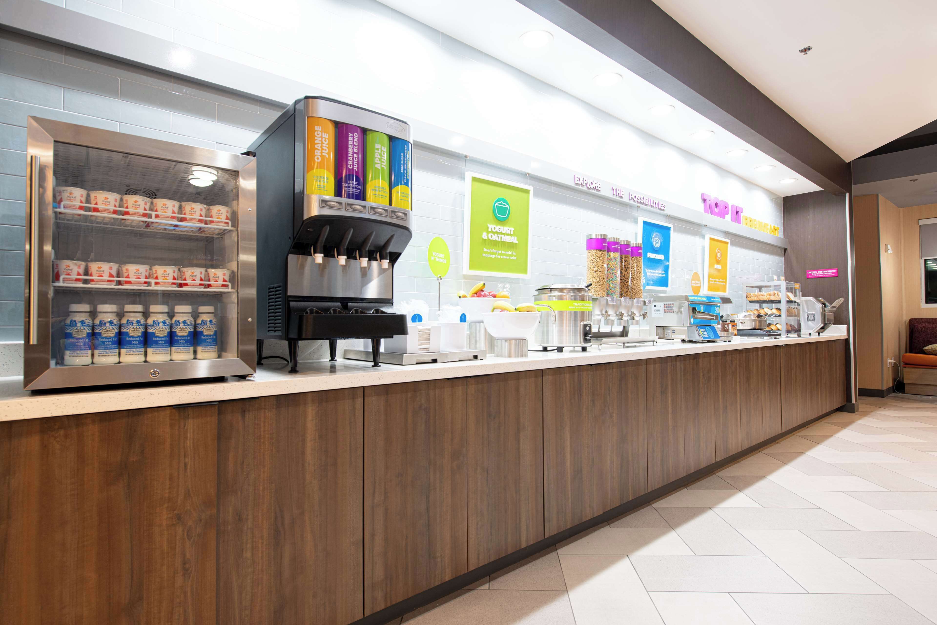 Una estación de café de autoservicio con un refrigerador que muestra leche y una máquina de café.